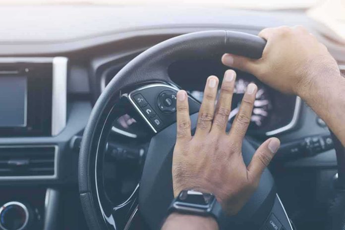 shutterstock_1682313487 Driver's hands on a car steering wheel pressing the horn