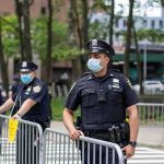 Police officers in masks standing by metal barricades outdoors