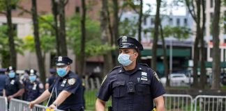 Cop Hits Homeless Man — Name Withheld Police officers in masks standing by metal barricades outdoors