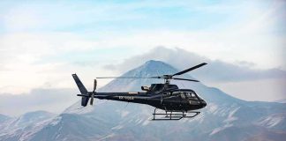 Black helicopter flying over rugged mountain range