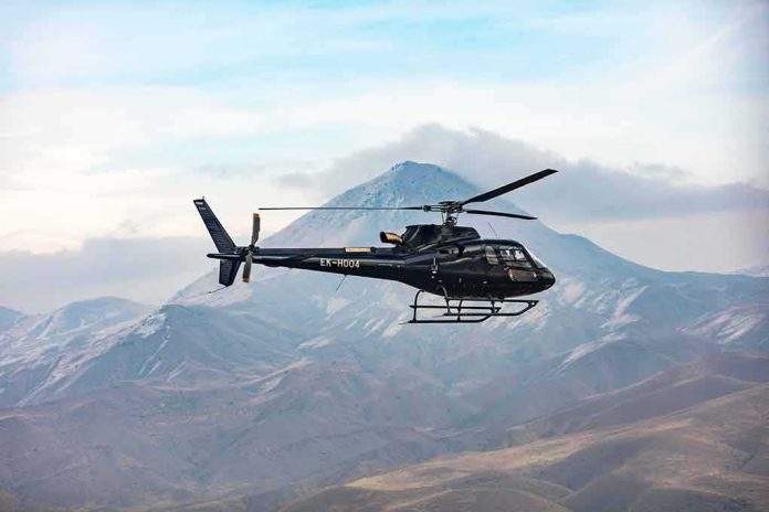 shutterstock_1912377844 Black helicopter flying over rugged mountain range