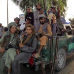 Safer Streets, Darker Future? Armed men sitting on a pickup truck.