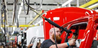 Trump Uses Michigan Auto Stop to Push His Economic Agenda Worker assembles red vehicle on factory line