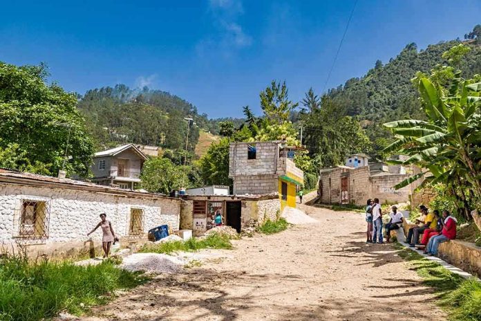 shutterstock_1164109183 Rural village street with people gathered and hills in the background