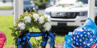Mother of Three. Young NYPD Officer Dies After Cosmetic Surgery Memorial wreath with white flowers and blue-black ribbons beside star-spangled balloons
