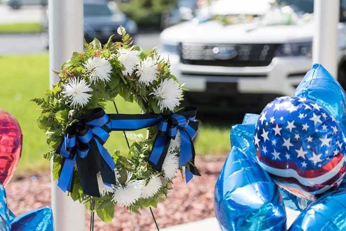 Memorial wreath with white flowers and blue-black ribbons beside star-spangled balloons