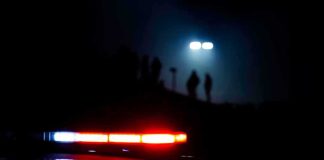 Pentagon Probes Alleged UFO Video Cover-Up Police car lights at night with silhouettes in the distance