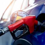 Red gasoline nozzle fueling a blue car