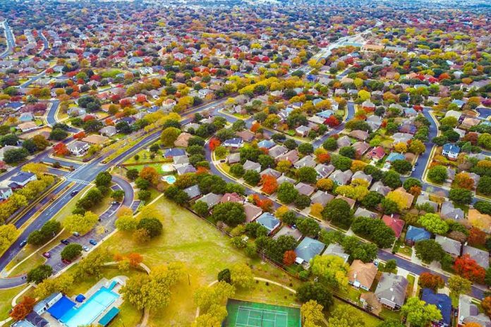 Aerial view of suburban neighborhood with tree-lined streets in autumn