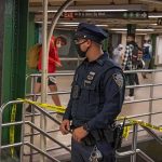 Man Shoved Onto NYC Subway Tracks—Attacker Still Missing Police officer stands in a subway station near caution tape