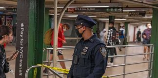 Police officer stands in a subway station near caution tape