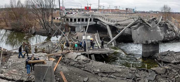 People crossing a destroyed concrete bridge over a river
