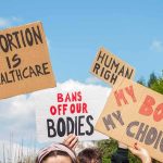 Massachusetts Ends 24-Week Abortion Limit Protesters hold cardboard signs at a rally outdoors