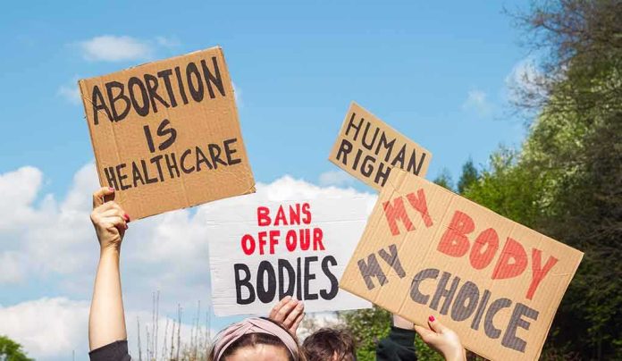 shutterstock_2154254667-1 Protesters hold cardboard signs at a rally outdoors