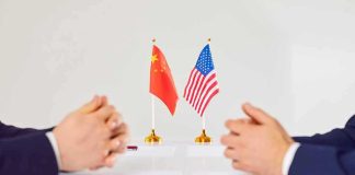 Disarmament Becomes Key Test for Gaza Peace Two diplomats sit across table with China and United States flags between them