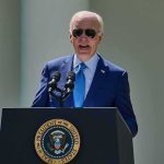 man in blue suit speaking at a podium with presidential seal