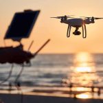 Drone hovering over beach at sunset