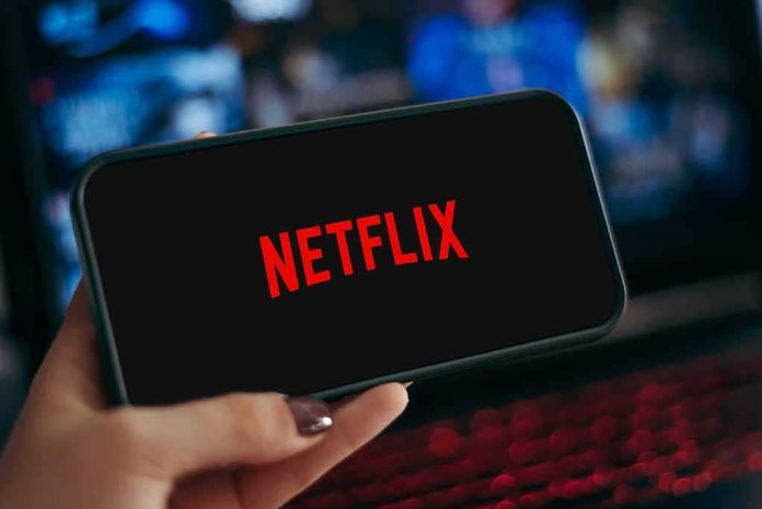shutterstock_2368379421 Smartphone displaying Netflix logo held in hand