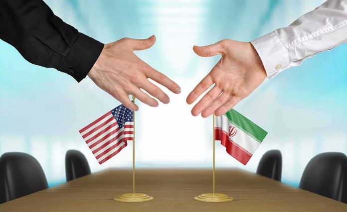 shutterstock_274494032 Two hands reaching to shake above US and Iran flags on a conference table