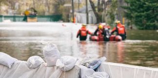 Sandbags stacked near a flooded street with rescue workers in a boat