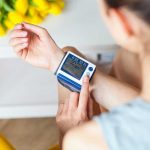 Person checking wrist blood pressure monitor indoors