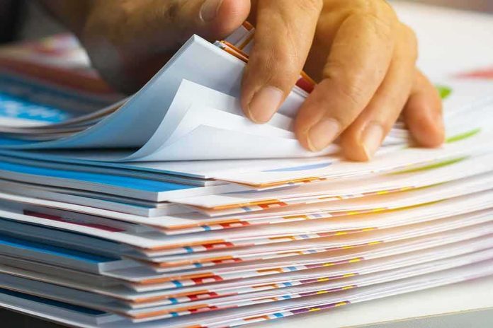 shutterstock_1023953008 Hand sorting through a stack of colorful documents