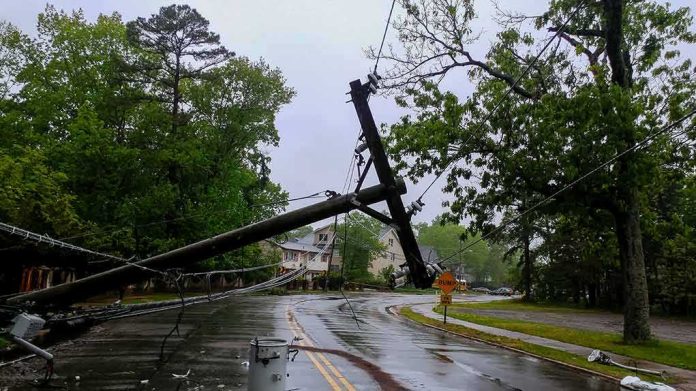 shutterstock_1093124054-1 Fallen utility poles blocking a wet suburban street
