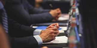 Guard Crime Claims Spark $5B Threat Hands of people in suits taking notes at a conference table