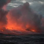 Volcanic steam plume over dark ocean at dusk