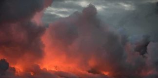Volcanic steam plume over dark ocean at dusk