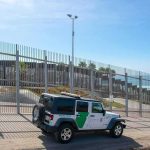 Shooting During Immigration Operation Border patrol SUV parked by tall metal fence near the coast