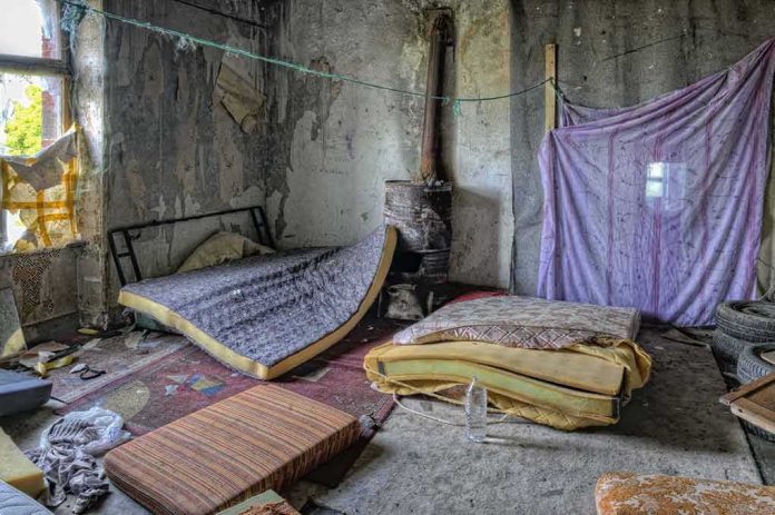 Abandoned room with torn mattresses and a rusty stove