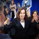 Kamala Harris speaks to a crowd as Maya Harris stands nearby