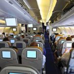 Violent Outburst Ends With Realty Exit Interior view of an airplane with passengers seated and using in-flight entertainment screens