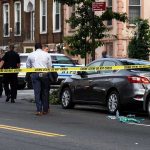 Homicide Ruling Leads to First Arrest Police at urban street crime scene with yellow tape around parked cars