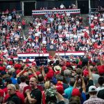 Crowd at a political rally facing a podium