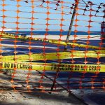 Diver Suffers Heavy Blood Loss in Offshore Shark Attack Orange safety net and yellow police tape blocking a beach access