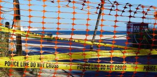 Orange safety net and yellow police tape blocking a beach access