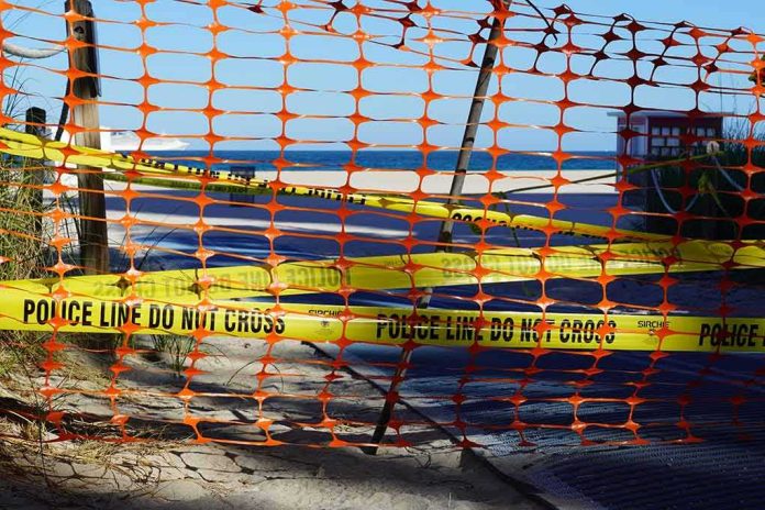 shutterstock_1687026364 Orange safety net and yellow police tape blocking a beach access