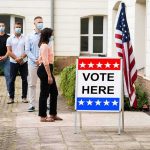 Wave Hits Colorado as 29-Year-Old Defeats House Veteran Voters wearing masks line up outside a polling place
