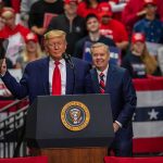 A $5,000 Check Could Depend on the Midterms two men at a podium during a large indoor rally