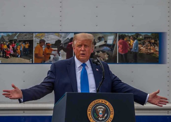 shutterstock_1804636972-1 Donald Trump speaks at a podium with arms outstretched