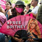 Knoxville Honors Music Legend With Colorful Tribute Parade Protester holding a pink fan with a slogan in a crowded rally