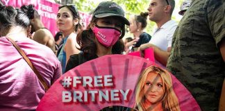 Protester holding a pink fan with a slogan in a crowded rally