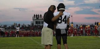 68-Game Winning Streak Comes to an End football coach with arm around player number 84 on sideline