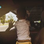 5-Year-Old Dies in Hot Car, Parents Charged Child leaning on car window from the back seat