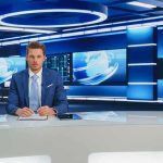 Newsroom Meltdown Engulfs 60 Minutes News anchor at a modern television studio desk