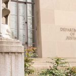 DOJ Charges 16 in Election Crime Cases Department of Justice building facade with stone sign and window