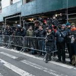 crowd of photographers behind barricades on a city street