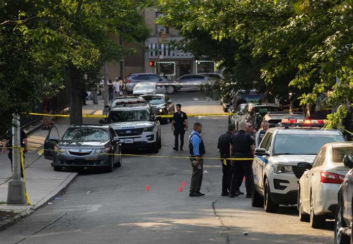 shutterstock_2330301305-1 Police officers secure a residential street with patrol cars and yellow tape